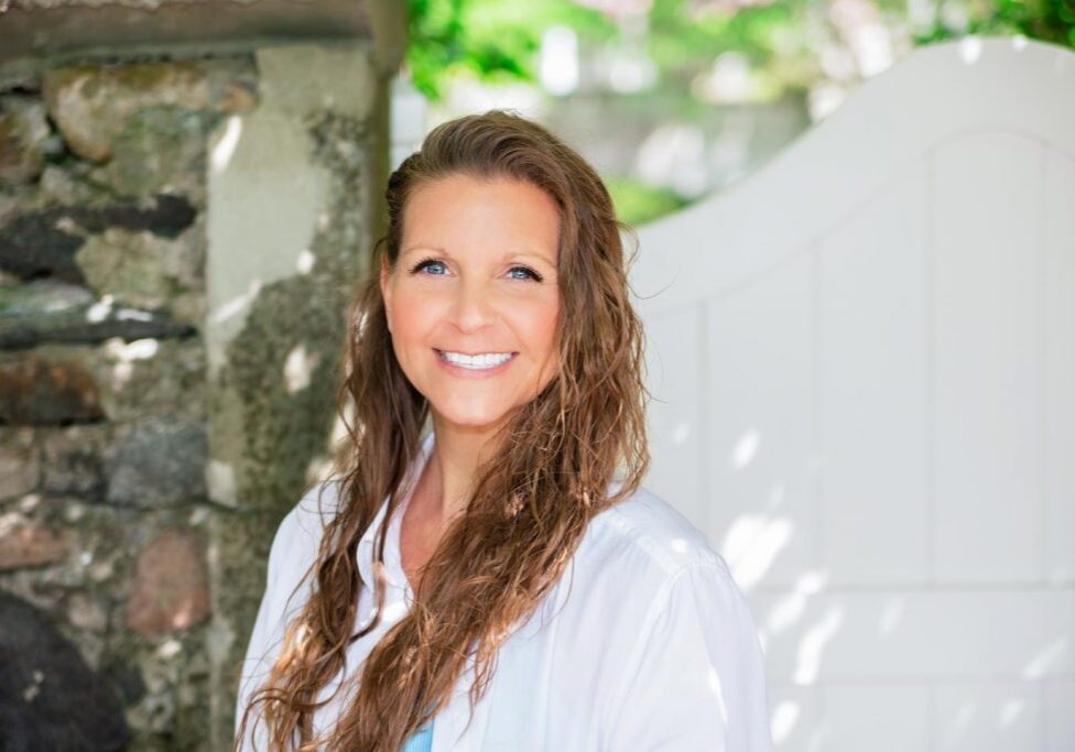 Nicole Bom smiles in front of a white gate